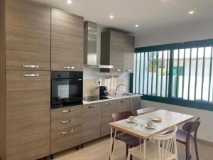 a kitchen with wooden cabinets and a table with chairs at Casa BAU in Los Pocillos