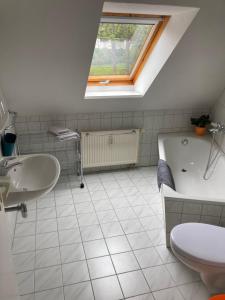 a bathroom with a sink and a tub and a toilet at Ferienwohnung Teichblick -Balkon- in Dresden +1 photo