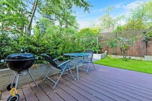 a bbq and a table and chairs on a deck at Charming Modern Chic Pad Summer House in London