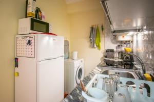 uma cozinha com um lavatório e um frigorífico branco em QuartosCotao em Agualva