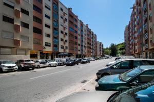 una concurrida calle de la ciudad con coches estacionados al costado de la carretera en QuartosCotao en Agualva