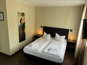 Schlafzimmer mit einem Bett mit weißer Bettwäsche und Kissen in der Unterkunft Das Bergschlösschen in Bamberg