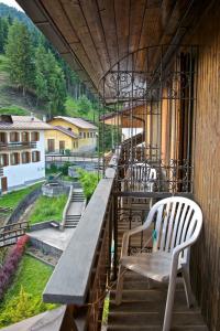 einen Balkon mit einer Bank und Stühlen auf einem Gebäude in der Unterkunft Albergo Ristorante Iris in Auronzo di Cadore