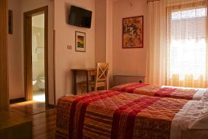 a bedroom with two beds and a table and a window at Albergo Ristorante Iris in Auronzo di Cadore