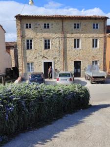 a large stone building with cars parked in front of it at Antico Casale Masini in SantʼAndrea di Compito
