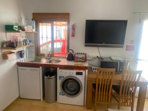 cocina con lavadora y TV en la pared en Casa Sol y Luna, en Arboleas