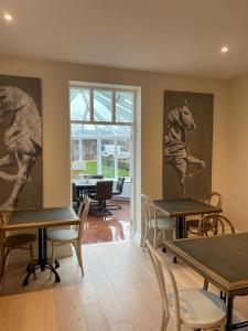 uma sala com mesas e cadeiras e pinturas na parede em Moulton Lawn House B&B 