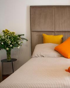 Una cama con almohadas amarillas y un jarrón de flores. en Dimora NiLu' en Margherita di Savoia