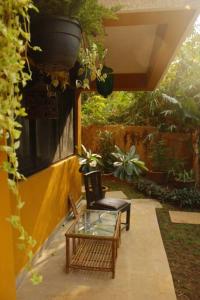 un patio con una mesa de cristal y una silla en The Burrow in South Goa. en Dabolim