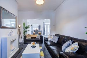 a living room with a black leather couch and a tv at Pass the Keys Beautiful House in SouthChurch in Southend-on-Sea