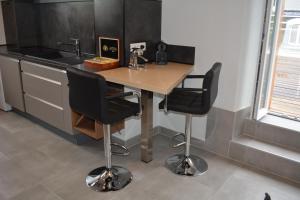 a kitchen with a wooden table and two bar stools at Appartement-terrasse parking privé Meublé de Tourisme 4 étoiles in Belfort