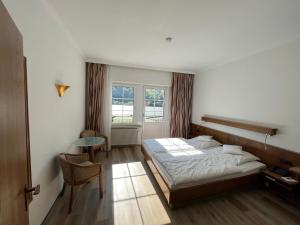 een slaapkamer met een bed, een tafel en een raam bij Hotel Schön in Aßmannshausen