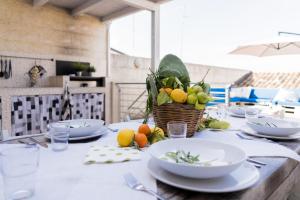 einem Tisch mit Tellern und einem Obstkorb darauf in der Unterkunft Casa Lina con terrazza in Canicattini Bagni