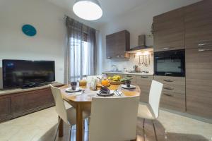 eine Küche mit einem Holztisch und weißen Stühlen in der Unterkunft Casa Lina con terrazza in Canicattini Bagni