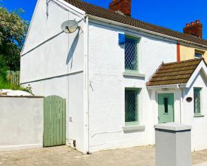 ein weißes Haus mit grüner Tür auf einer Straße in der Unterkunft Beautiful Two Bedroom Cottage in Morriston