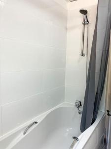 a bathroom with a tub with a shower and a sink at Beautiful Two Bedroom Cottage in Morriston
