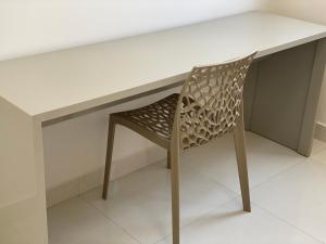 une chaise assise à un bureau avec une table blanche dans l'établissement Apto novo, com ar, acesso rápido ao centro, à Uberlândia 12 autres photos