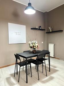 una mesa de comedor negra con sillas y un jarrón de flores en Grey Apartment en Caiazzo