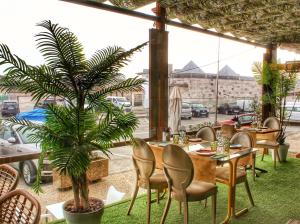 a restaurant with a table and chairs and a palm tree at Hotel Spa El Muelle de Suances in Suances