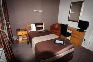 a bedroom with a bed and a desk and a computer at Glyn Peris Guest House in Llanberis