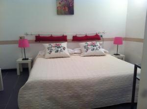 Hotel Pensione Moderna في بوناسولا: غرفة نوم بسرير كبير بها مصباحين ورديين