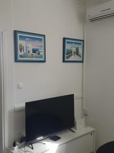 een televisie op een bureau met twee foto's aan de muur bij Apartma IRENA in Novi Vinodolski