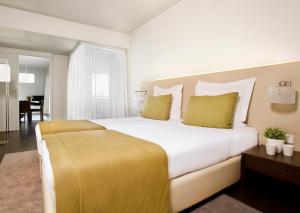 ein Schlafzimmer mit einem großen weißen Bett mit gelben Kissen in der Unterkunft Aqualuz Troia Rio by The Editory in Troia