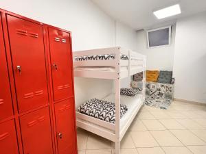 Split It Hostel في سبليت: غرفة مع سرير بطابقين أبيض وخزانة حمراء