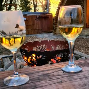 Dois copos de vinho branco numa mesa com uma fogueira. em Fox Lodge at Heygates Lodging - with hot tub 