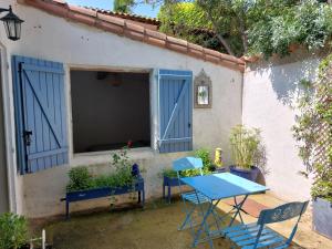 uma mesa e cadeiras em frente a uma casa com portas azuis em Gîte entre mer et Cévennes em Le Cailar