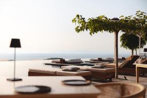 un grupo de tumbonas y mesas con vistas al océano en Canaves Epitome - Small Luxury Hotels of the World en Oia