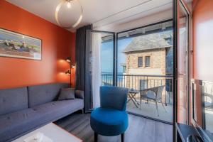 ein Wohnzimmer mit einem blauen Stuhl und einem großen Fenster in der Unterkunft Logis Hôtel Ker Mor in Perros-Guirec