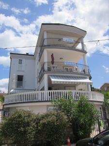 a tall white building with a balcony on it at Apartments Antonia in Malinska