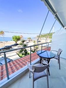 balkon ze stołem i krzesłami oraz plażą w obiekcie Ionian View B&B w mieście Himara