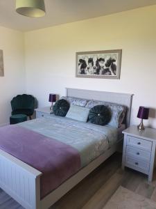 a bedroom with a bed with two lamps and a chair at Redland Cottage in Orkney