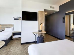 a hotel room with two beds and a flat screen tv at B&B HOTEL Argenteuil in Argenteuil