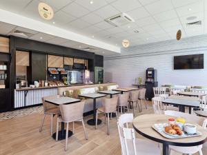 a restaurant with tables and chairs and a counter at B&B HOTEL Argenteuil in Argenteuil