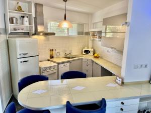 a kitchen with a table and blue chairs at Stunning View Seaside 1-Bed Apartment in Saronida in Saronida
