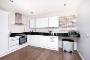 a kitchen with white cabinets and black counter tops at Cozy 2BR London Flat with Workspace and City Views in London