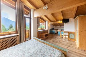 ein Schlafzimmer mit einem Bett in einem Zimmer mit Fenstern in der Unterkunft Chalet Piereni in Fiera di Primiero