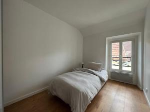 een witte slaapkamer met een bed en een raam bij Au cœur du Bourg - La Celle St Cloud. in La Celle-Saint-Cloud