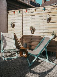 duas cadeiras e uma mesa em frente a uma cerca em Appartement avec patio em Sainte Anne d'Auray