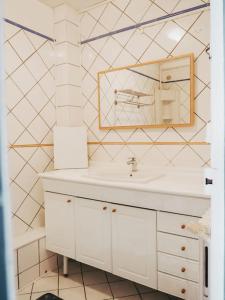 uma casa de banho branca com um lavatório e um espelho em Appartement avec patio em Sainte Anne d'Auray