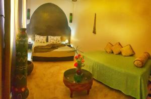 een slaapkamer met 2 bedden en een tafel met een groen bed bij Riad Karmanda in Marrakesh