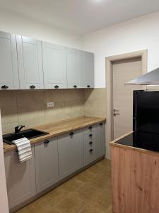 een keuken met witte kasten en een zwarte magnetron bij Tik-tak apartment in Petrovaradin