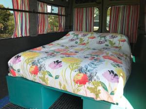 Una cama en un autobús con un edredón floral en Berty the campervan en Carbis Bay