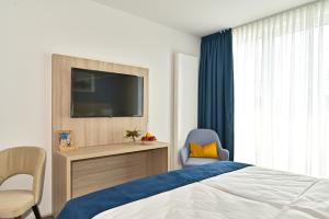a bedroom with a bed and a tv and a chair at HotelHafenWedel in Wedel