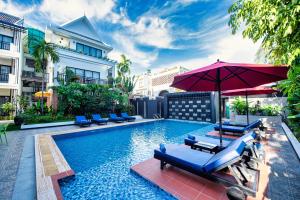 a swimming pool with lounge chairs and an umbrella at Peak Elite Boutique in Siem Reap