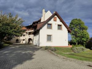 Casa blanca con techo marrón en una entrada en Kőrisfa Apartman, en Alsópáhok