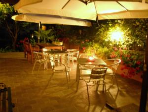 a patio with tables and chairs under an umbrella at Locanda Villa Moderna in Genoa